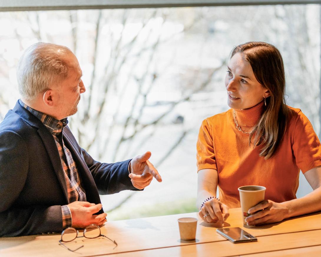 un homme et une femme discutant avec un café dans les mains